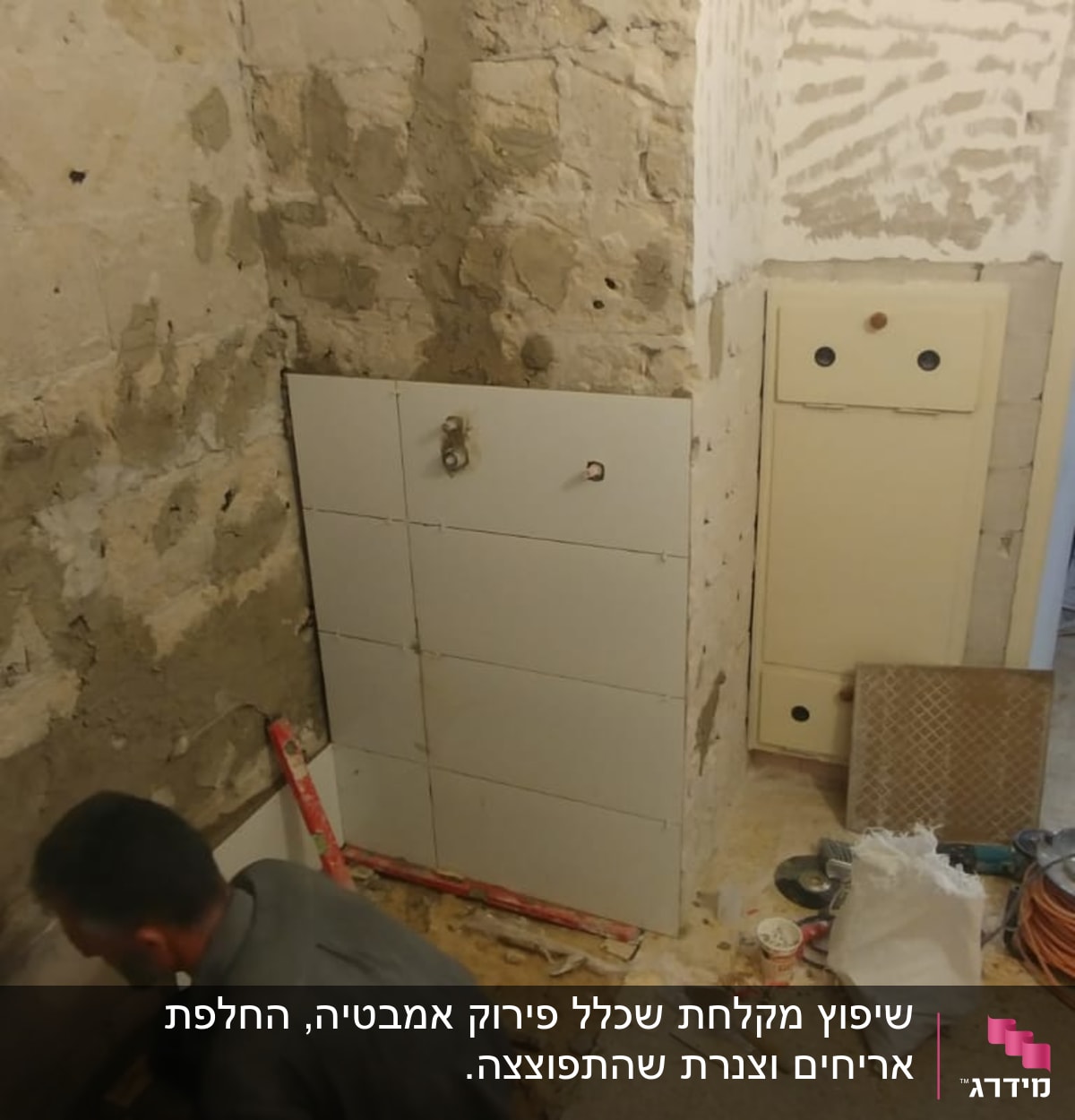 עובד מתקין אריחים על קיר במהלך שיפוץ